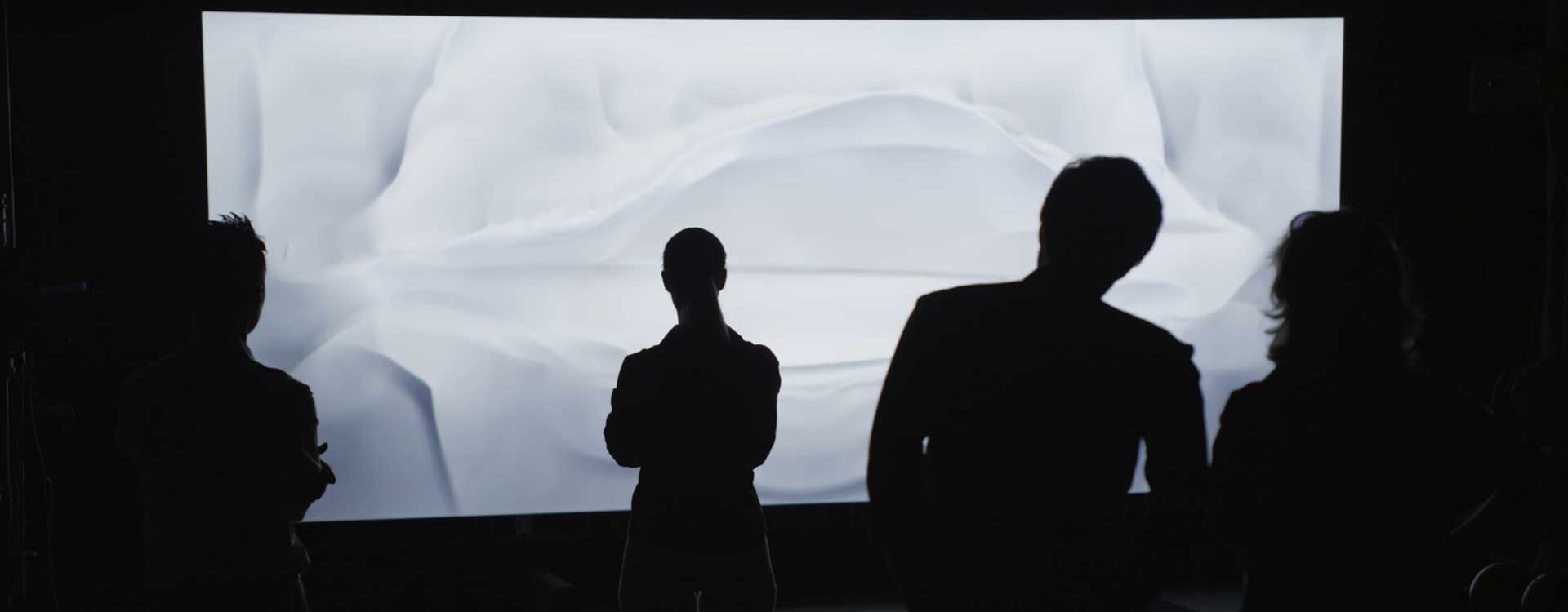 Audience in front of display. Still from Mercedes-Benz Commercial.